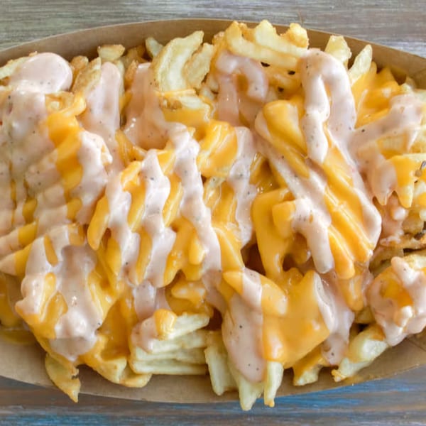 Close-up of Brake Burger Garage's waffle fries topped with melted cheese and a creamy sauce.