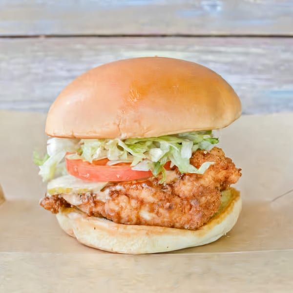 Brake Burger Garage's crispy fried chicken sandwich with lettuce, tomato, and pickles on a bun.